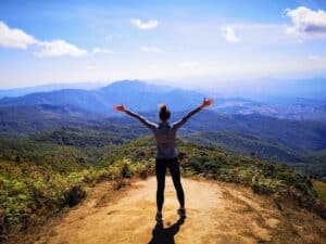 Women standing on the edge of a mountain with arms outstretched, Thailand