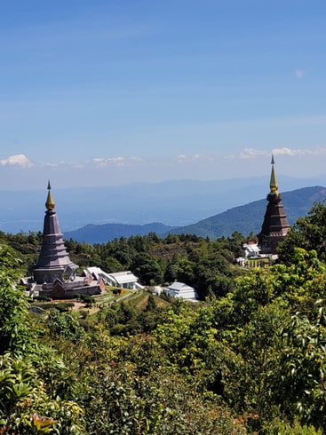 The Royal twin pagodas stand high above the thick tree line, as mountains can be seen in the background at Doi Inthanon National Park, Thailand