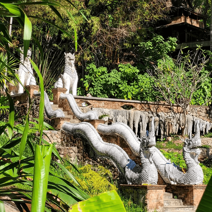 Two dragons stand at either side at the top of stone steps surrounded by rainforest at Wat Phra Lat temple in Chiang Mai, Thialand