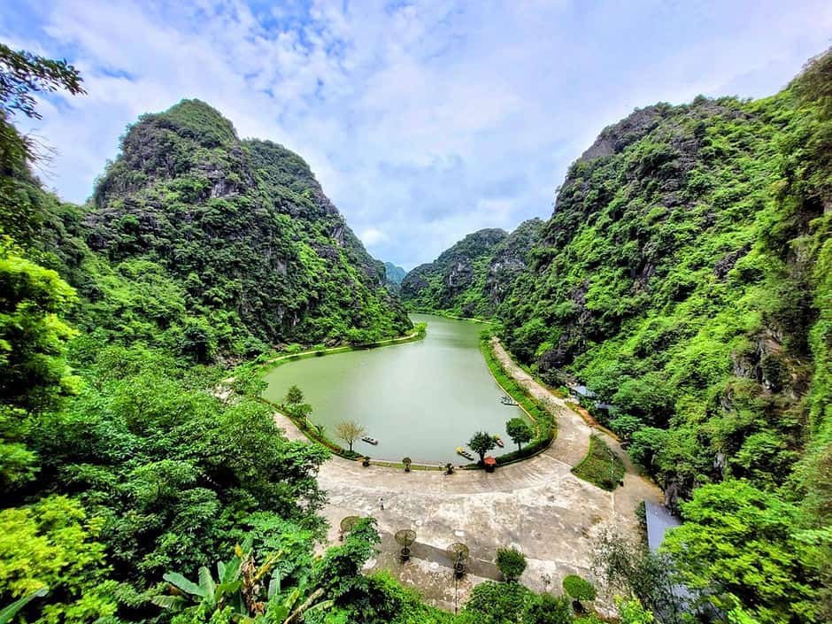 The small Am Tien lake sits surrounded by tree-covered mountains in Trang An, Vietnam