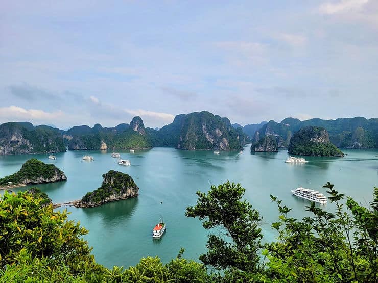 Cruise boats float on the blue water of Halong Bay in Vietnam, surrounded by limestone mountains