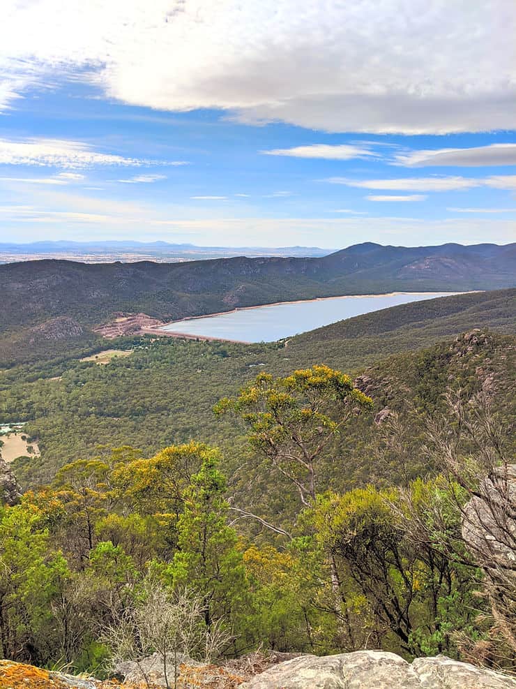 Lake Bellfield sits flat and rectangular in the centre of a valley of lush green forest, framed by uneven mountain peaks in the Grampians National Park