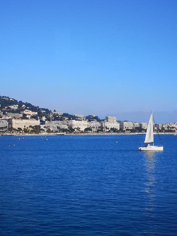 A small sailing boat glides into Cannes Port  