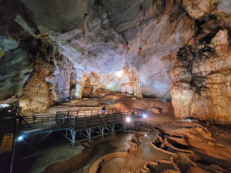 Woman standing on a wooden boardwalk in a vast chamber of the incredible Paradise Cave in Phong Nha, Vietnam