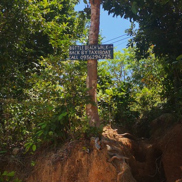 A wooden sign indicating the start of the Bottle beach hiking trail in Koh Phangan
