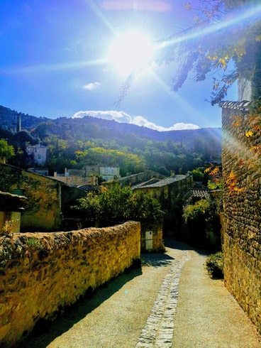 A Narrow path framed by cobblestone walls leads to the hilltop village of Oppede le Vieux