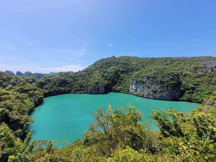 A bright Emerald lake is enclosed by limestone walls covered in thick forest in Ang Thong Marine Park, Thailand