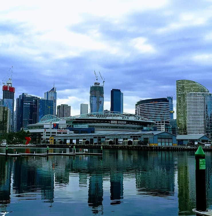 The Marvel events stadium sits on the water's edge in Melbourne's Docklands, surroudned by modern high rise buildings, which reflect in the still water of the harbour