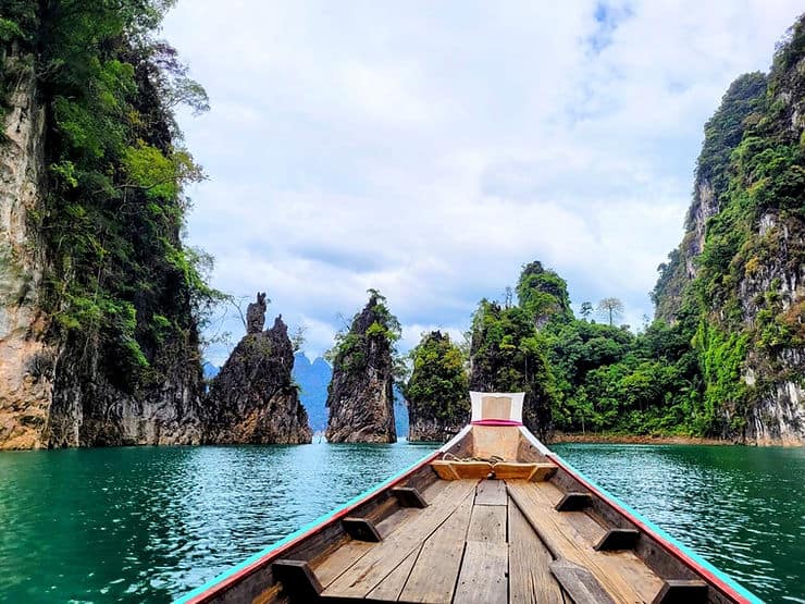 The front nose of a longtail boat can be seen sat on Cheow Lan lake, surrounded by limestone cliffs