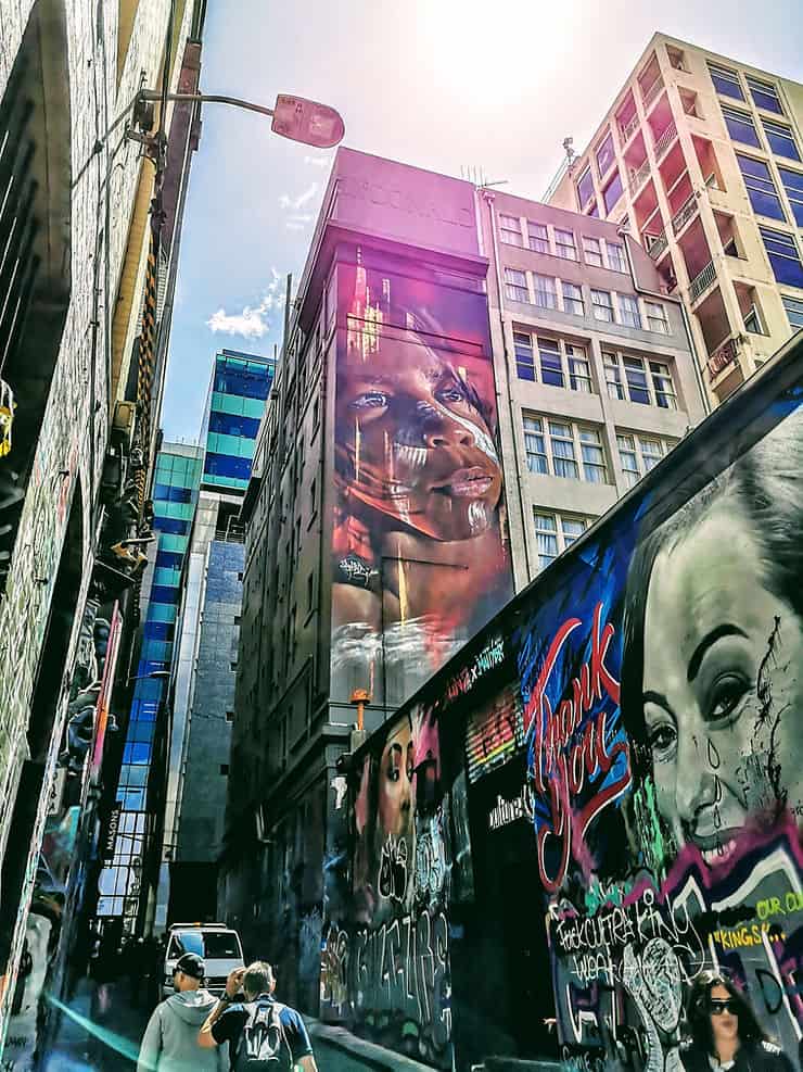 Two large portraits are painted onto the side of tower buildings by graffiti artists in Melbourne's CBD