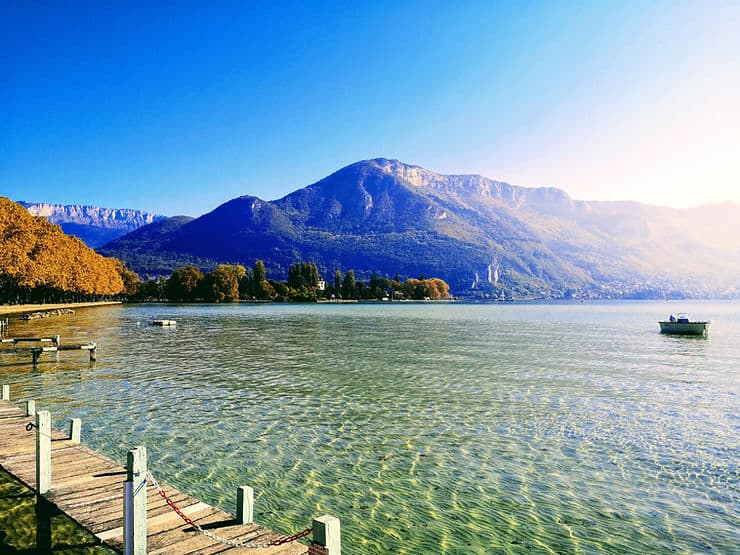The crystal clear water of Lake Annecy Alpine lake in France is surrounded by mountain ranges