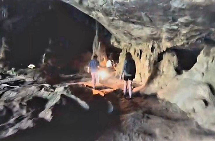 A local female guide carries an oil lamp leading a woman through the dark Tham Lod cave, in Pai, Thailand