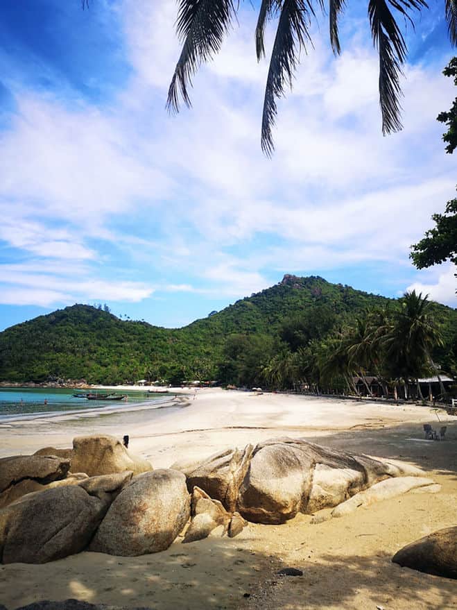 Golden sands and clear blue water of Bottle beach surrounded by thick palm tree forests, in Koh Phangan, Thailand