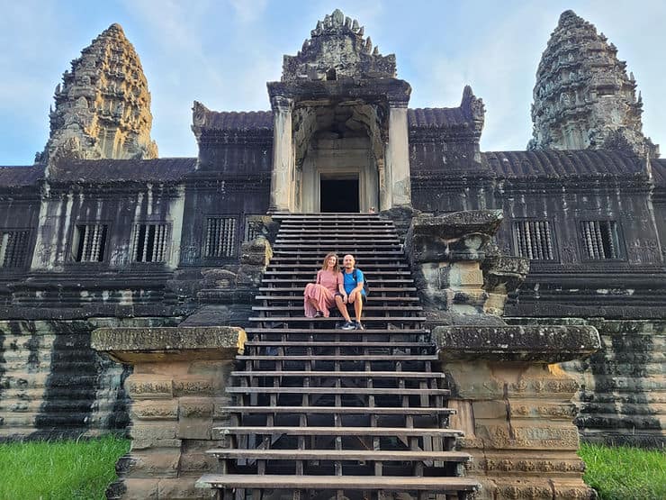 A couple sitting on the steps of Angkor Wat in Cambodia