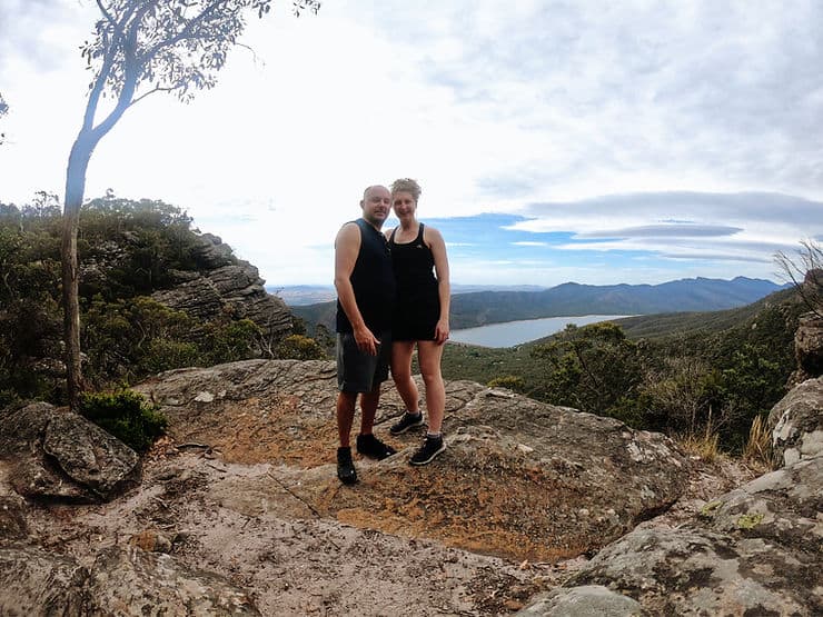 Standing on a large rock high above sea level, with the large rectangle-shaped Lake Bellfield in the background, surrounded by mountain peaks