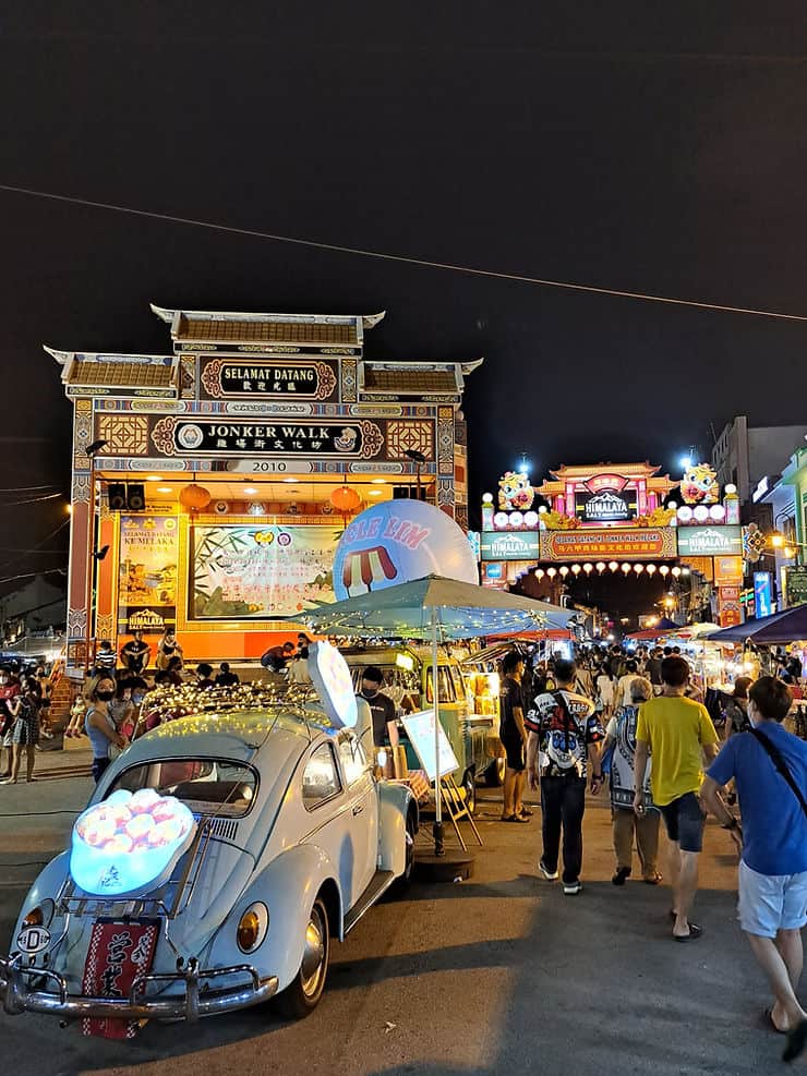 Crowds of people walk through the neon lights of Jonker night market in Melaka, Malaysia 