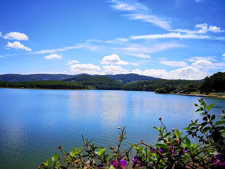 A blue lake, surrounded by forest covered hills in Dalat