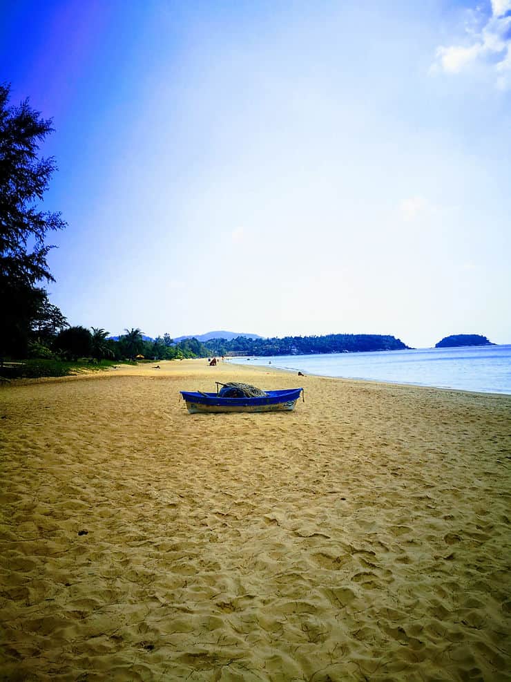 The golden sands of Karon beach stretch for 4km, backed by green trees. The beach is almost deserted, except for one small fishing boat sitting in the centre. 