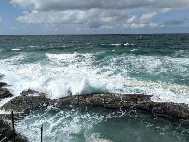 Waves crash over the rocks into Newcastle's famous Bogey Hole swimming pool in New South Wales, Australia 