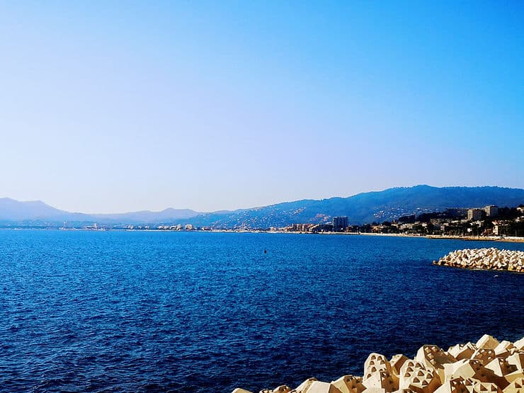 The picturesque shoreline of Cannes, with deep blue sea and backed by mountain ranges