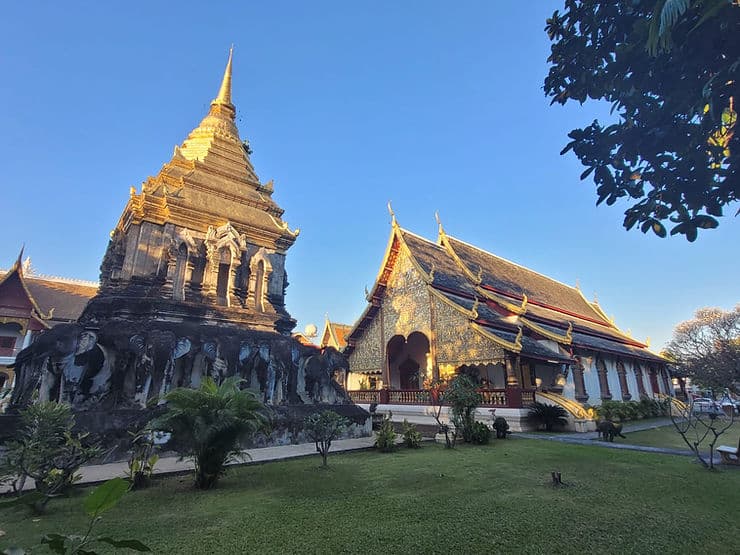 A gold Chedi temple and a large golden temple house in Wat Chiang Man sit in green parkland