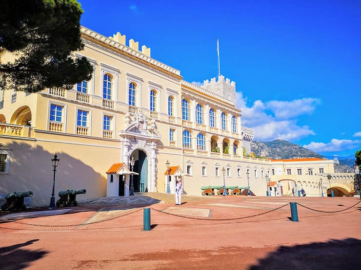 A guard stands in front of a white Palace building in Monaco.
