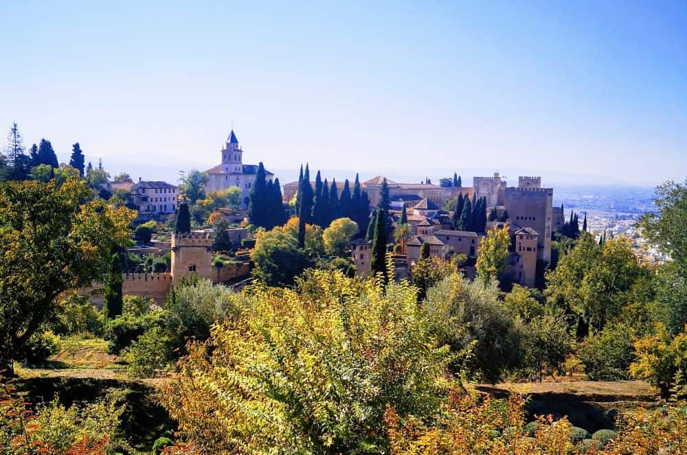 The sprawling complex of Alhambra sits amongst the trees atop a hill overlooking the city of Granada, Spain.