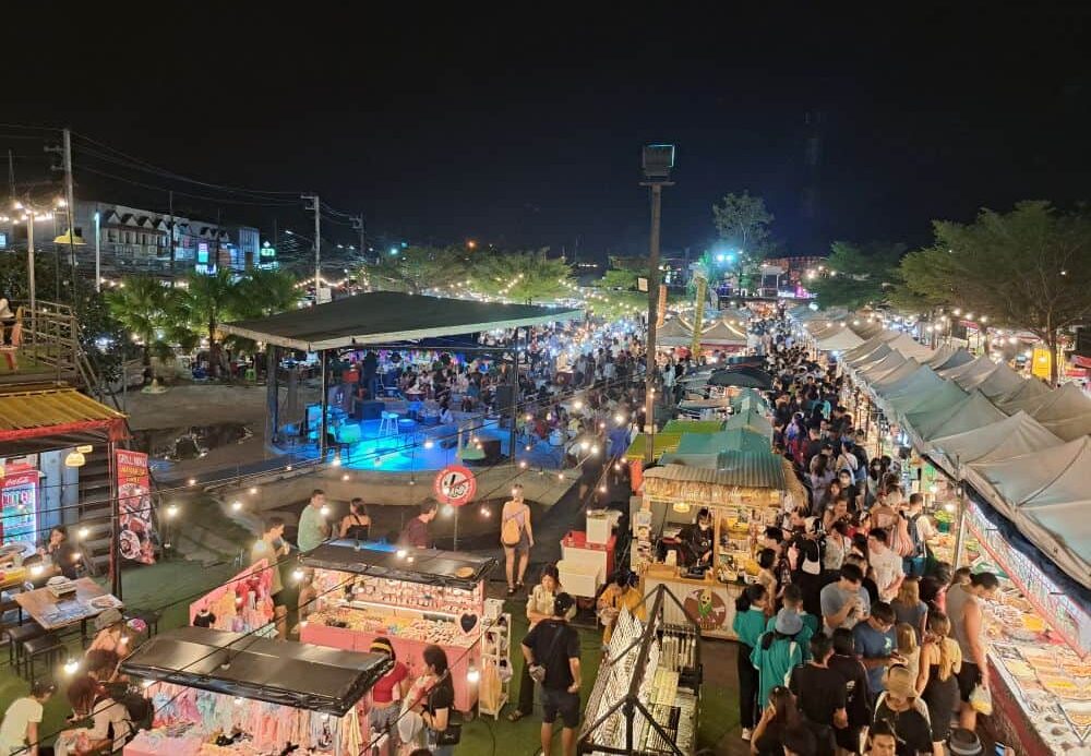 Street food vendors sell local Thai food under a canopy of gazebos in a night square