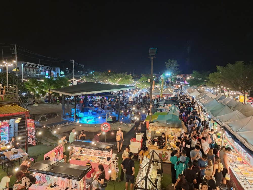Street food vendors sell local Thai food under a canopy of gazebos in a night square