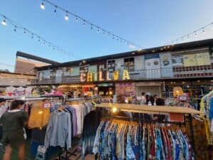 Rows of clothes hang on rails outside a shop made from a converted shipping container