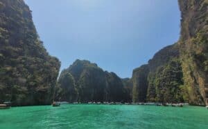 A green lagoon is surrounded by steep limestone mountains