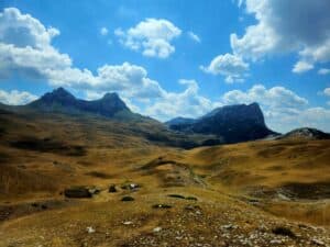 A mountain range sits in front of a blue cloudy sky