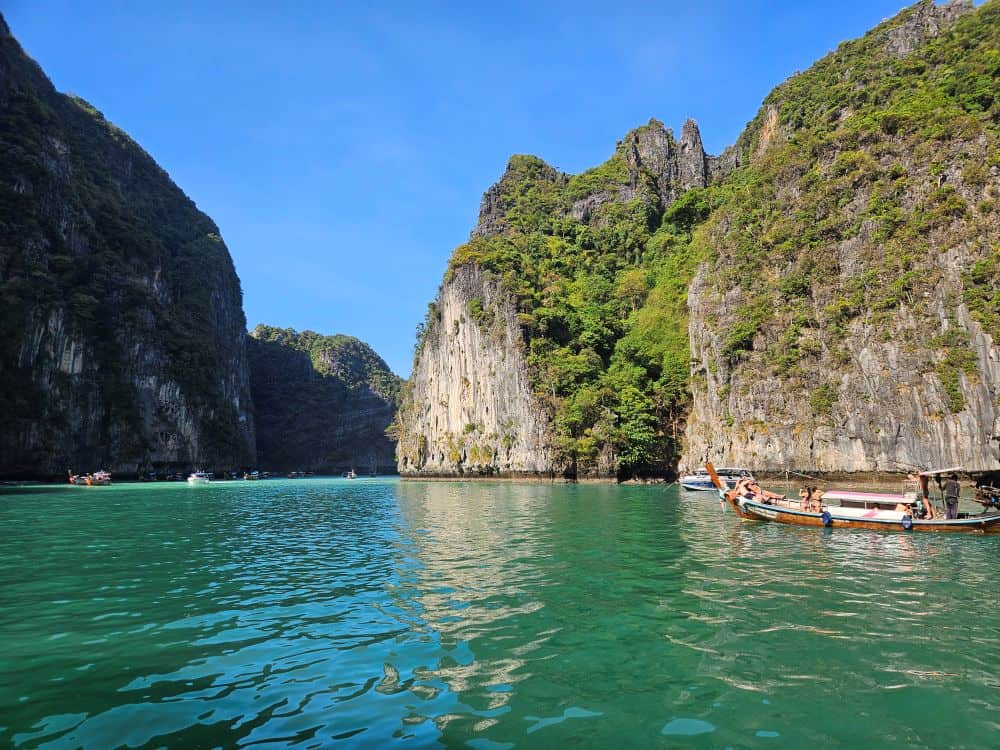 A calm turquoise bay surrounded by tree-covered limestone cliffs.